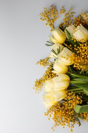 Bouquet with beautiful tulips and mimosa flowers on light grey background, top view. Space for text