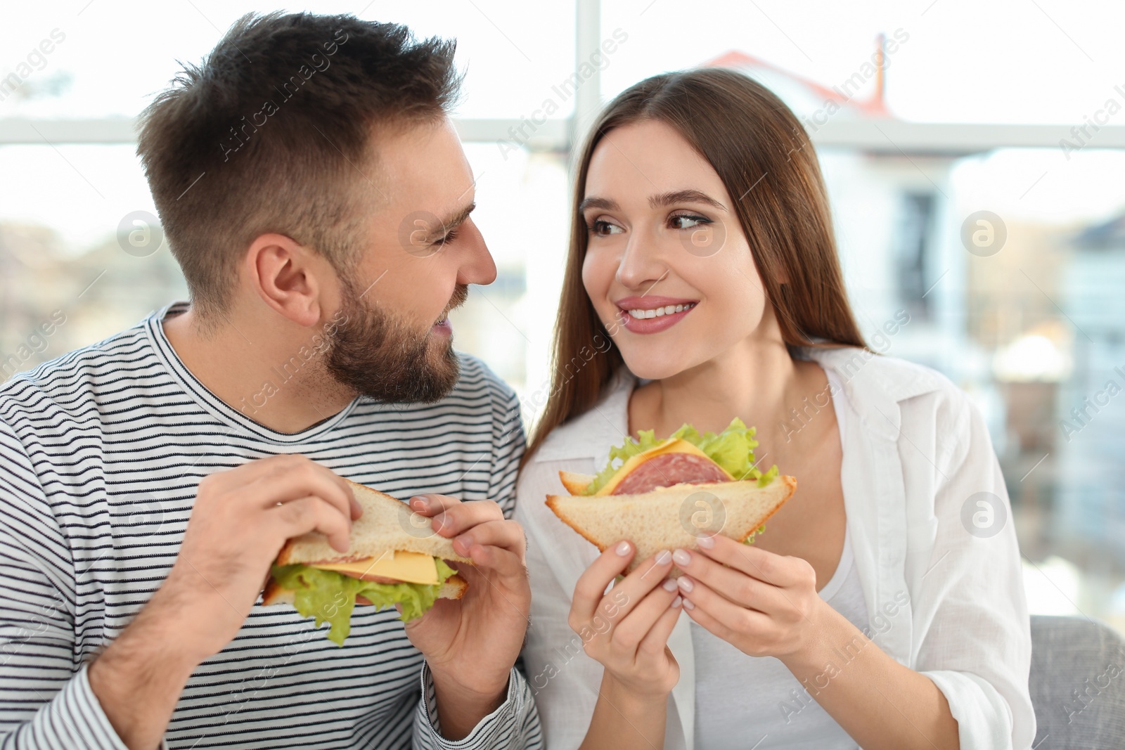 Photo of Happy couple having breakfast with sandwiches at home