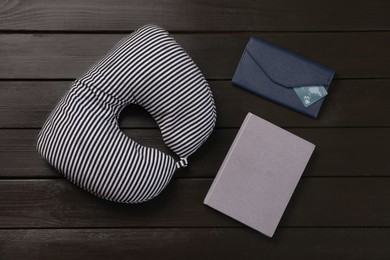 Photo of Striped travel pillow, notebook and wallet with credit card on dark wooden background, flat lay