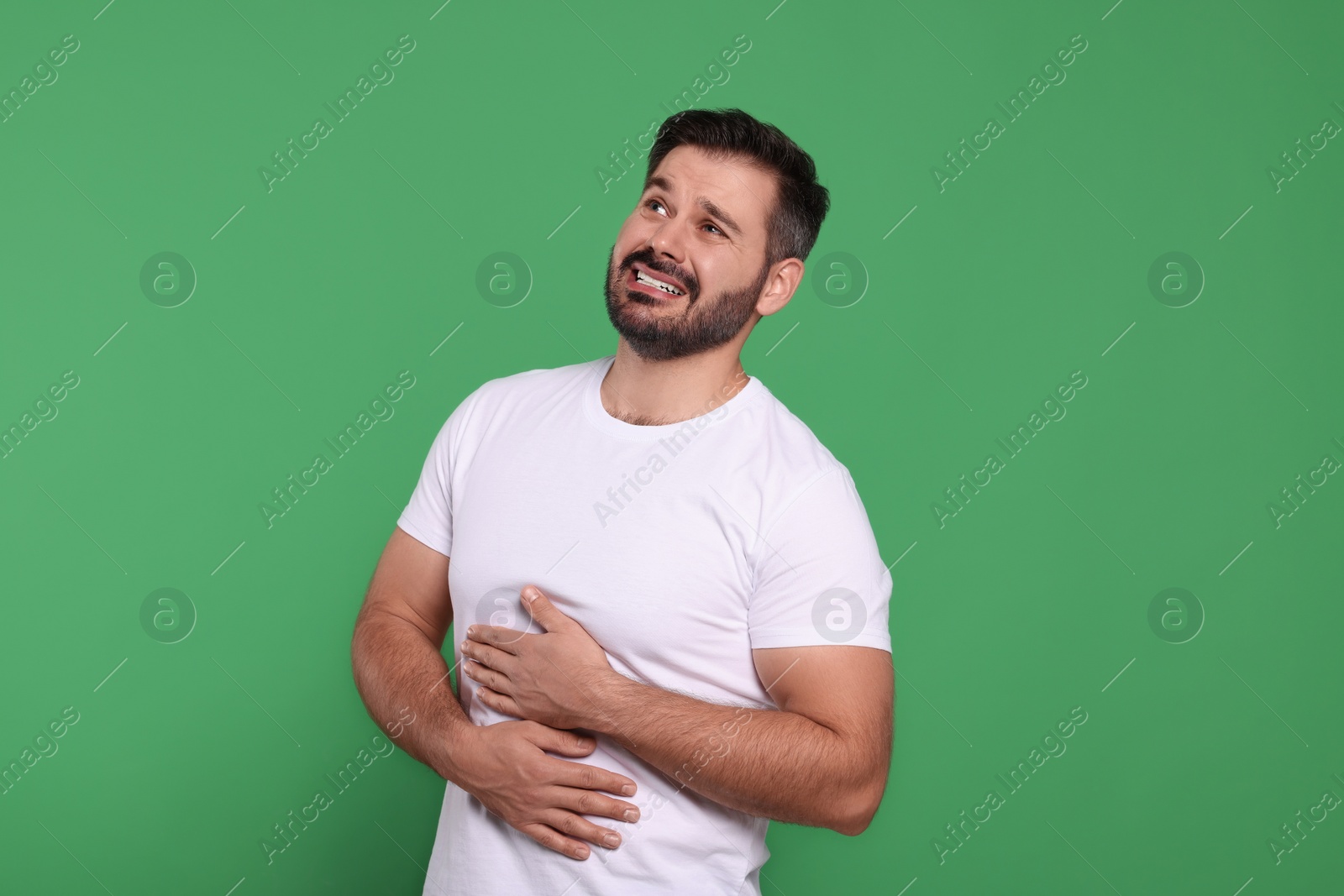 Photo of Man suffering from stomach pain on green background