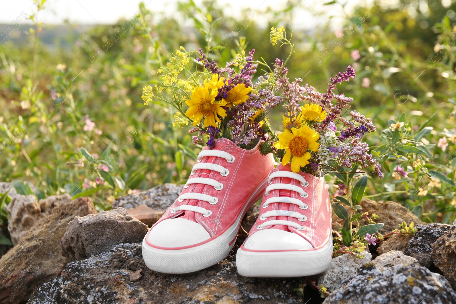 Photo of Shoes with beautiful flowers on stones outdoors