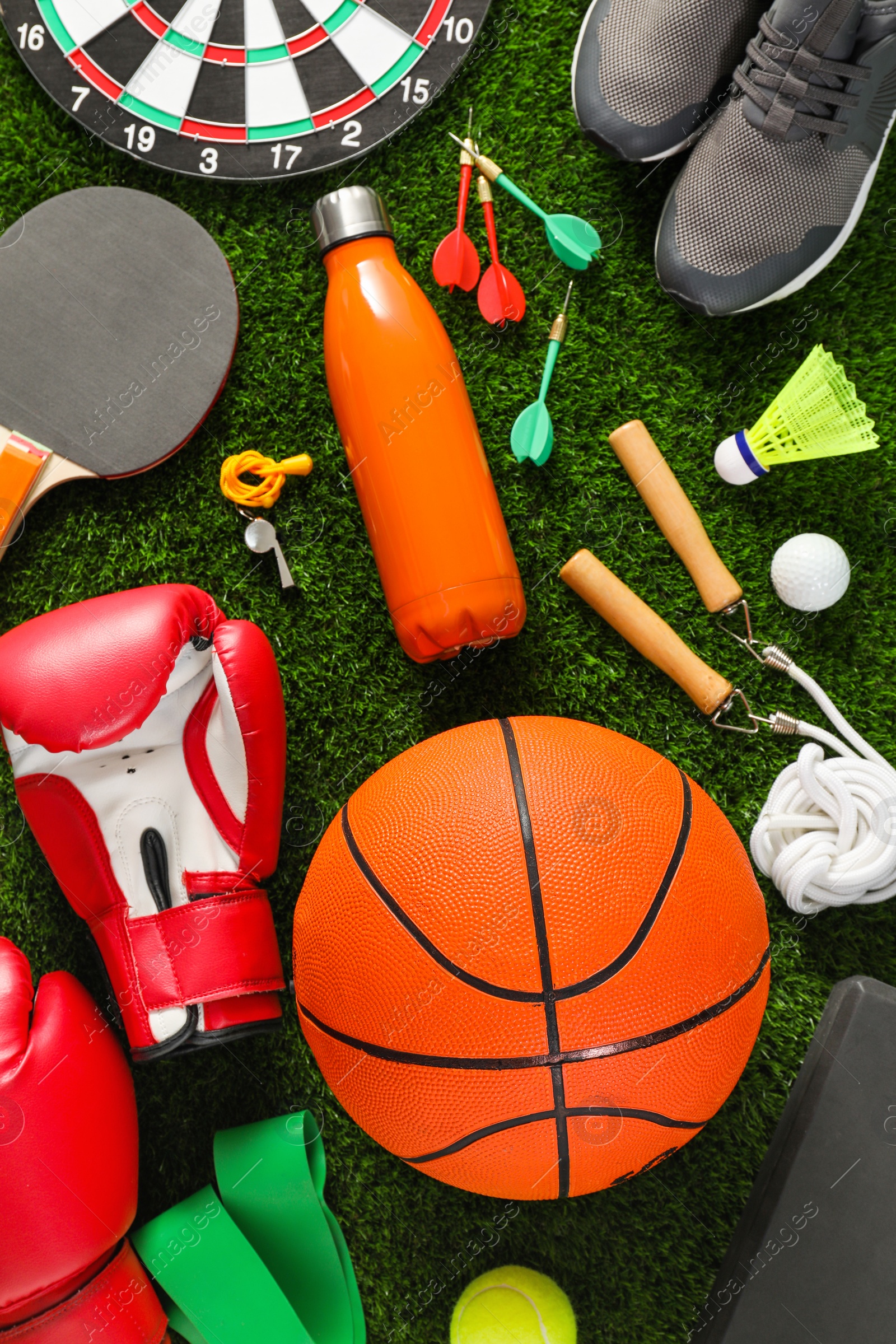 Photo of Different sport equipment on green grass, flat lay