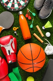 Photo of Different sport equipment on green grass, flat lay