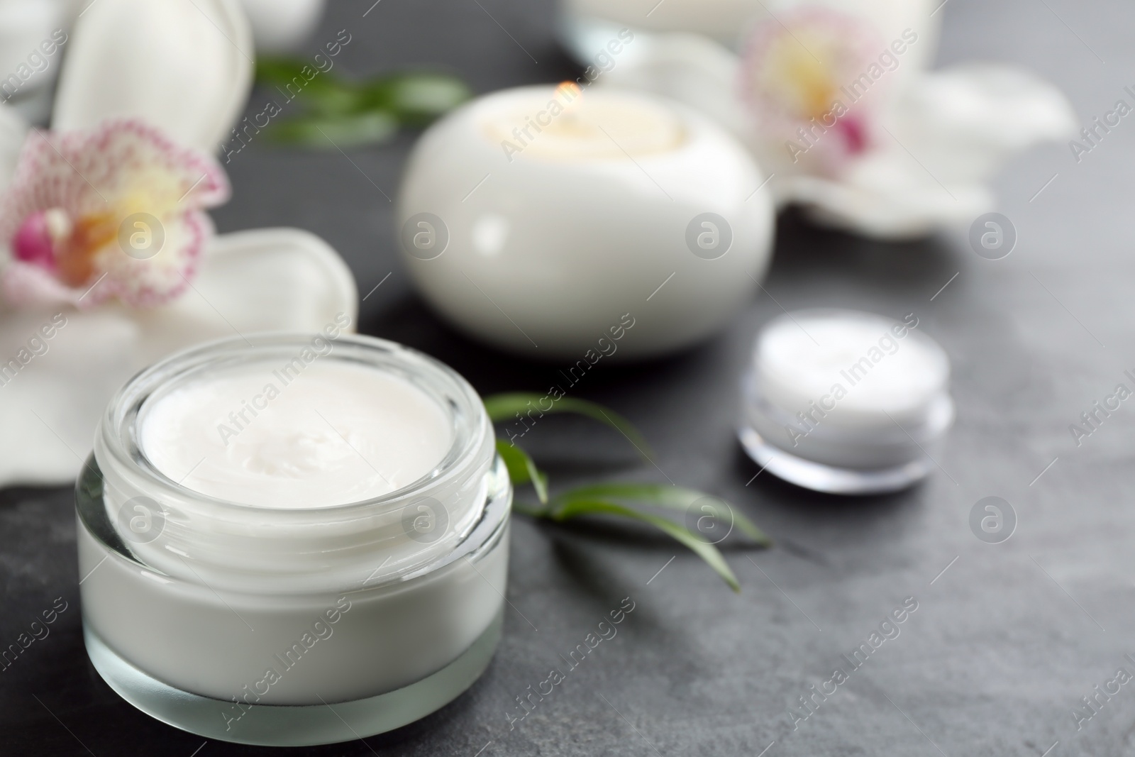 Photo of Beautiful spa composition with cosmetic products and flowers on black table, closeup. Space for text