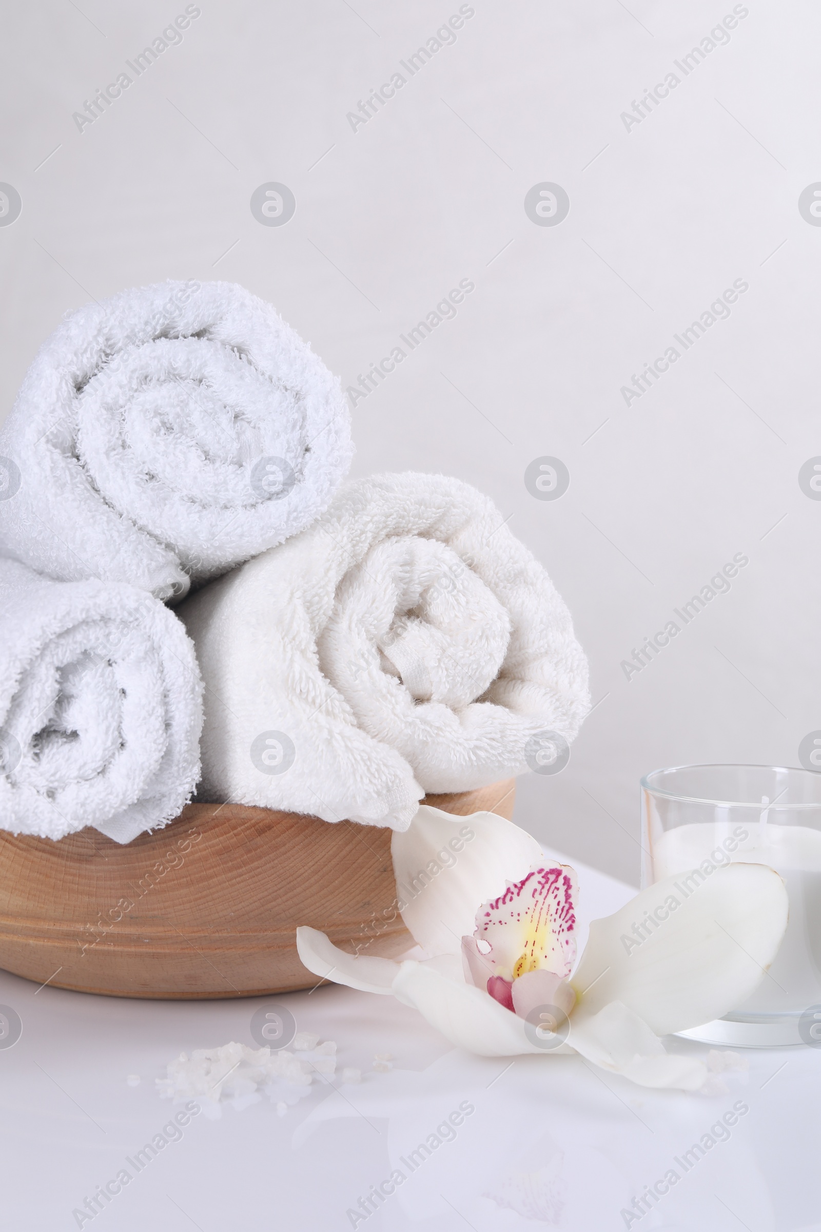 Photo of Spa composition with towels, orchid flower, candle and sea salt on white table