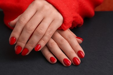 Photo of Woman with red polish on nails on black background, closeup