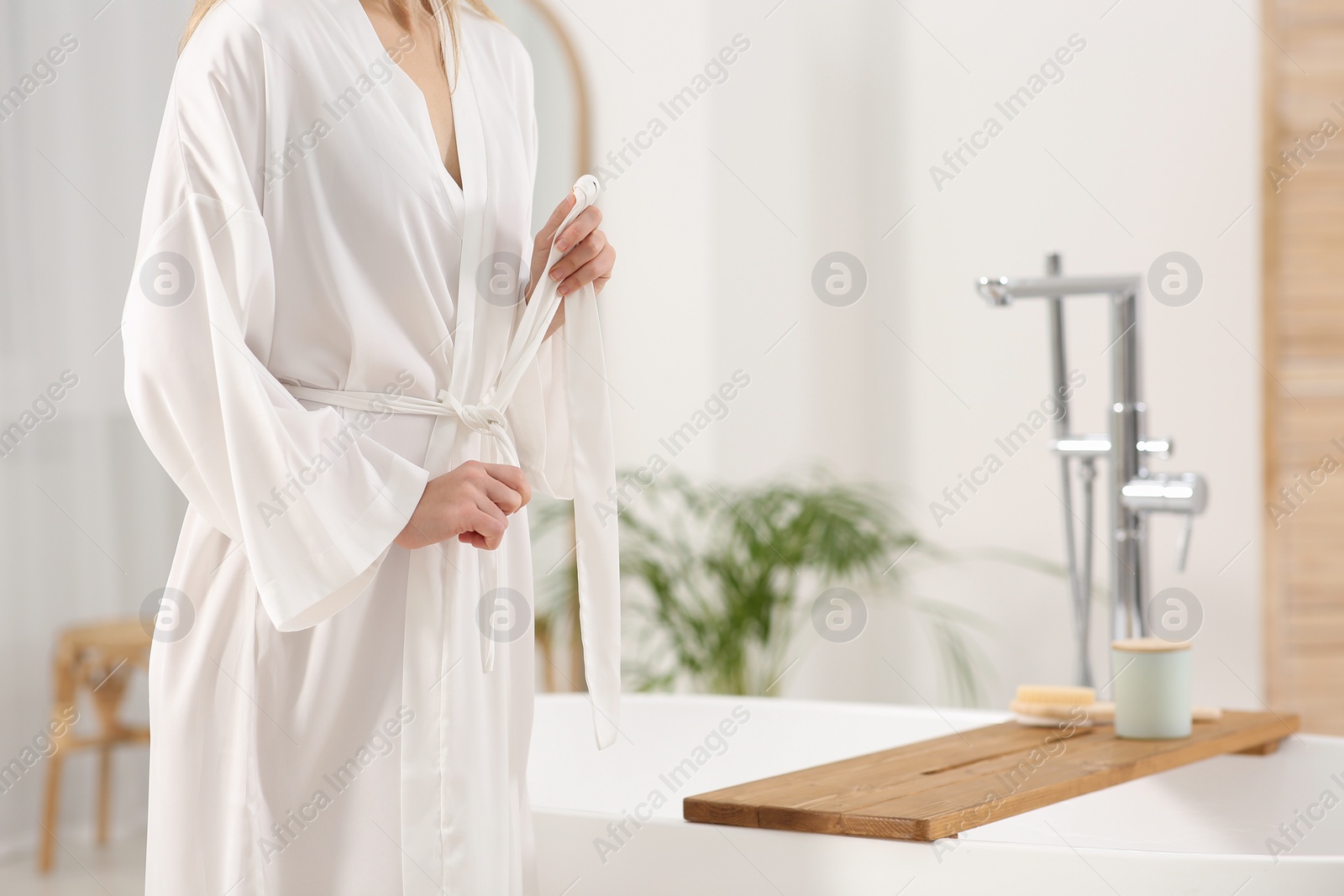 Photo of Woman wearing white robe near tub in bathroom, closeup