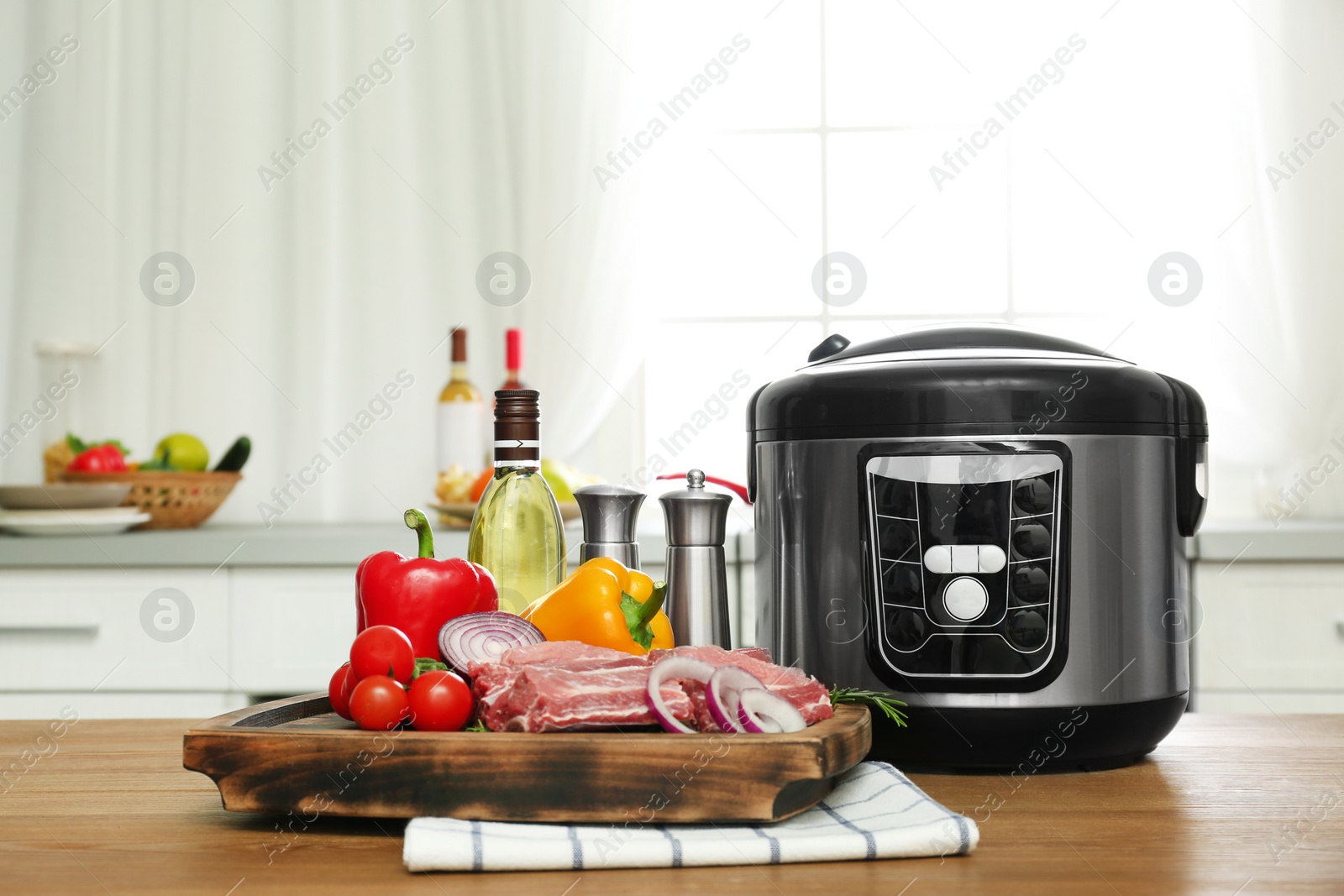 Photo of Modern multi cooker and products on wooden table in kitchen. Space for text