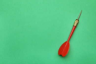 Photo of Red dart arrow on green background, top view with space for text