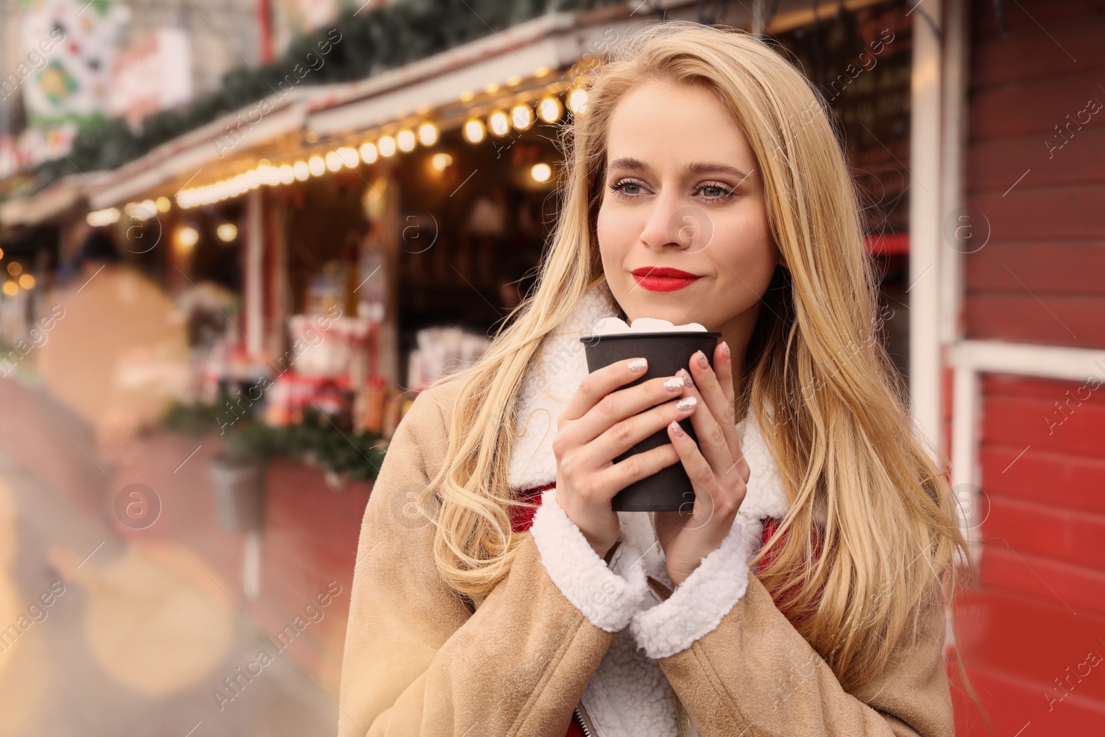 Photo of Young woman with hot drink at Christmas fair