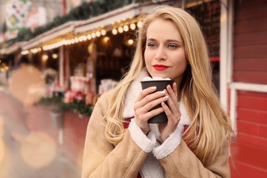 Photo of Young woman with hot drink at Christmas fair