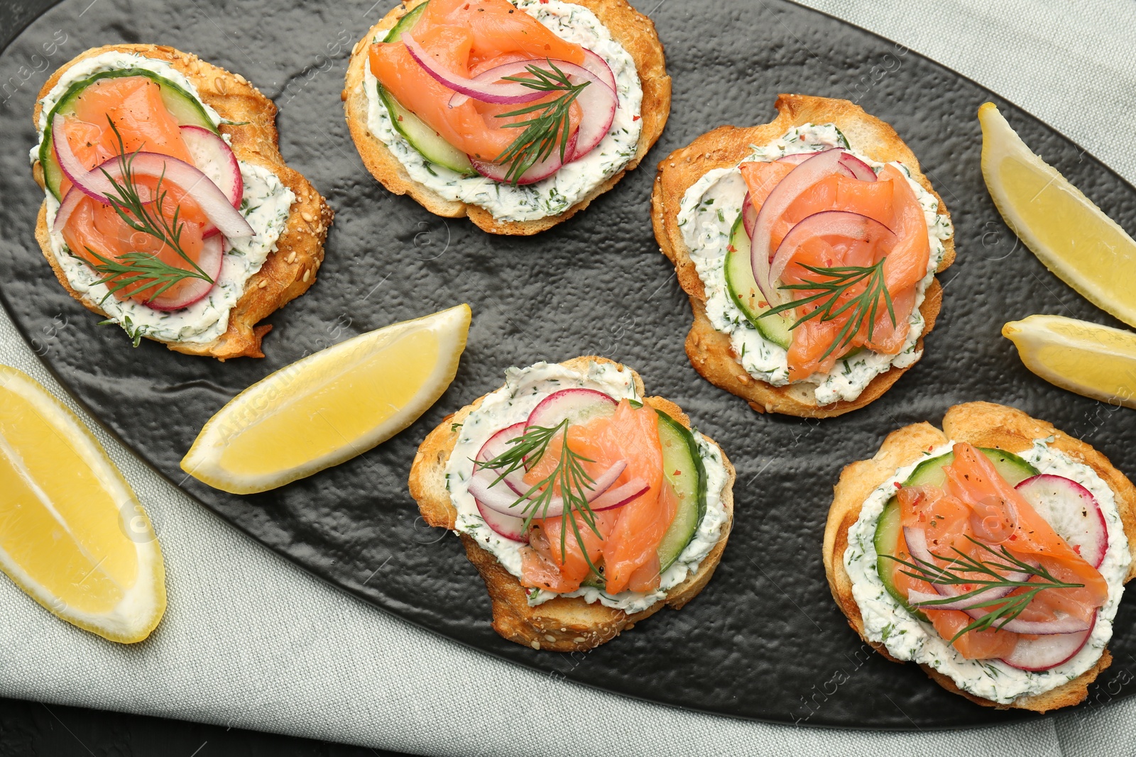 Photo of Tasty canapes with salmon, cucumber, radish and cream cheese on table, top view