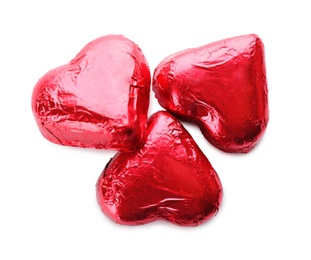 Heart shaped chocolate candies in red foil on white background, top view