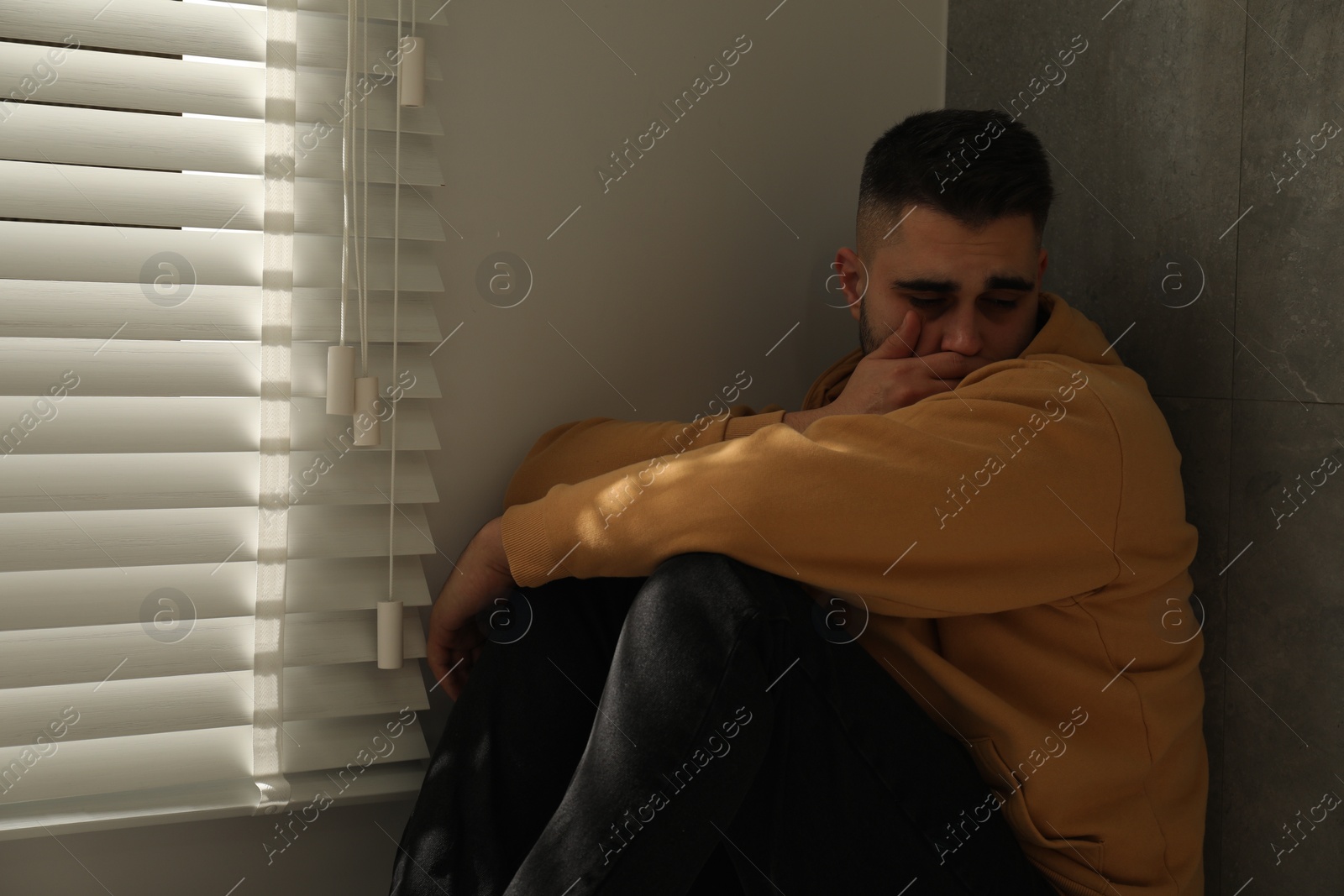 Photo of Sad man sitting near window. Space for text