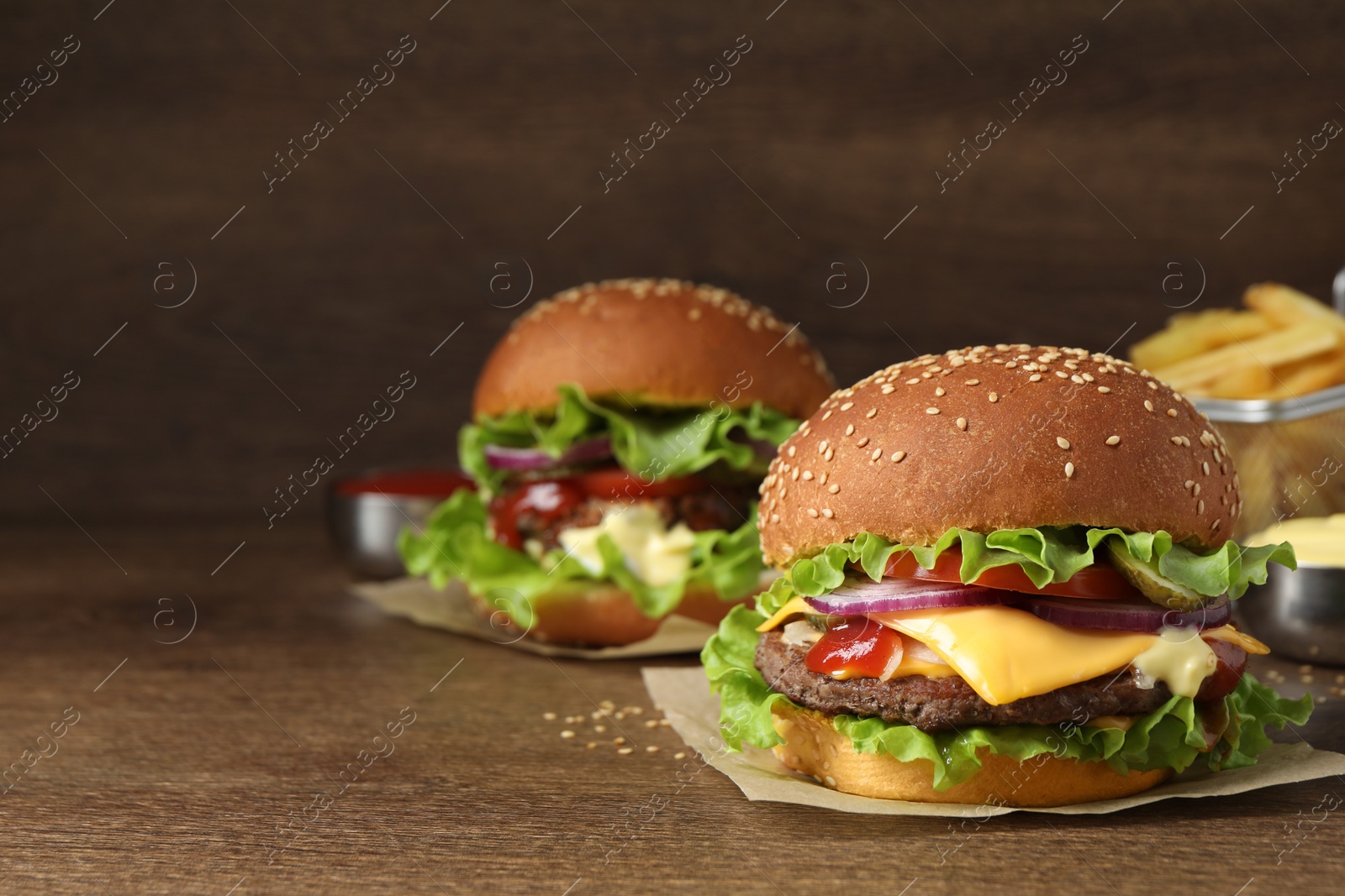 Photo of Delicious burgers with beef patty on wooden table, space for text