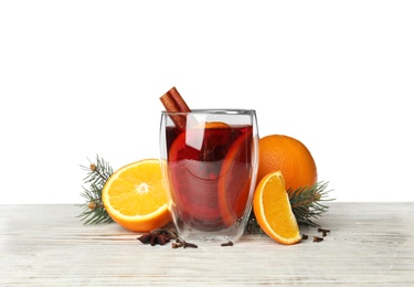 Photo of Glass of mulled wine with fir branch, cinnamon and orange on table against white background