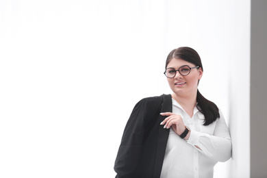 Photo of Beautiful overweight businesswoman posing on light background, space for text. Plus size model