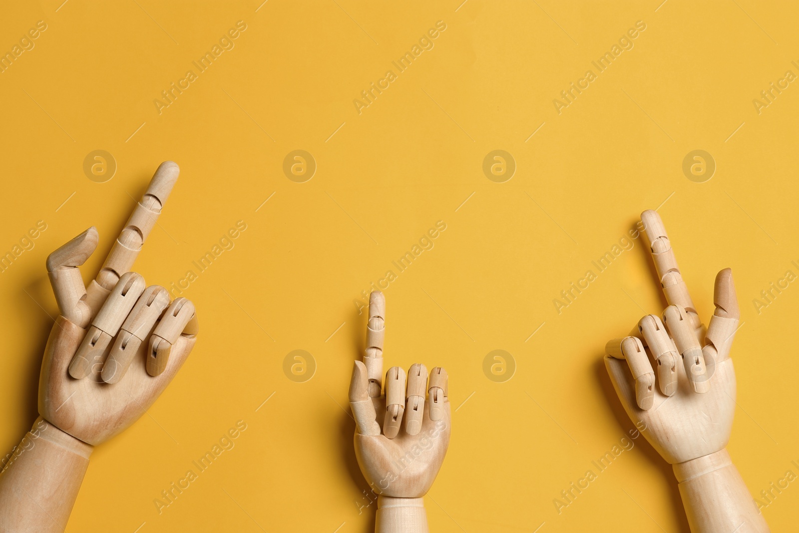 Photo of Wooden mannequin hands on yellow background, flat lay