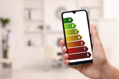 Energy efficiency. Man using smartphone with colorful rating on display indoors, closeup