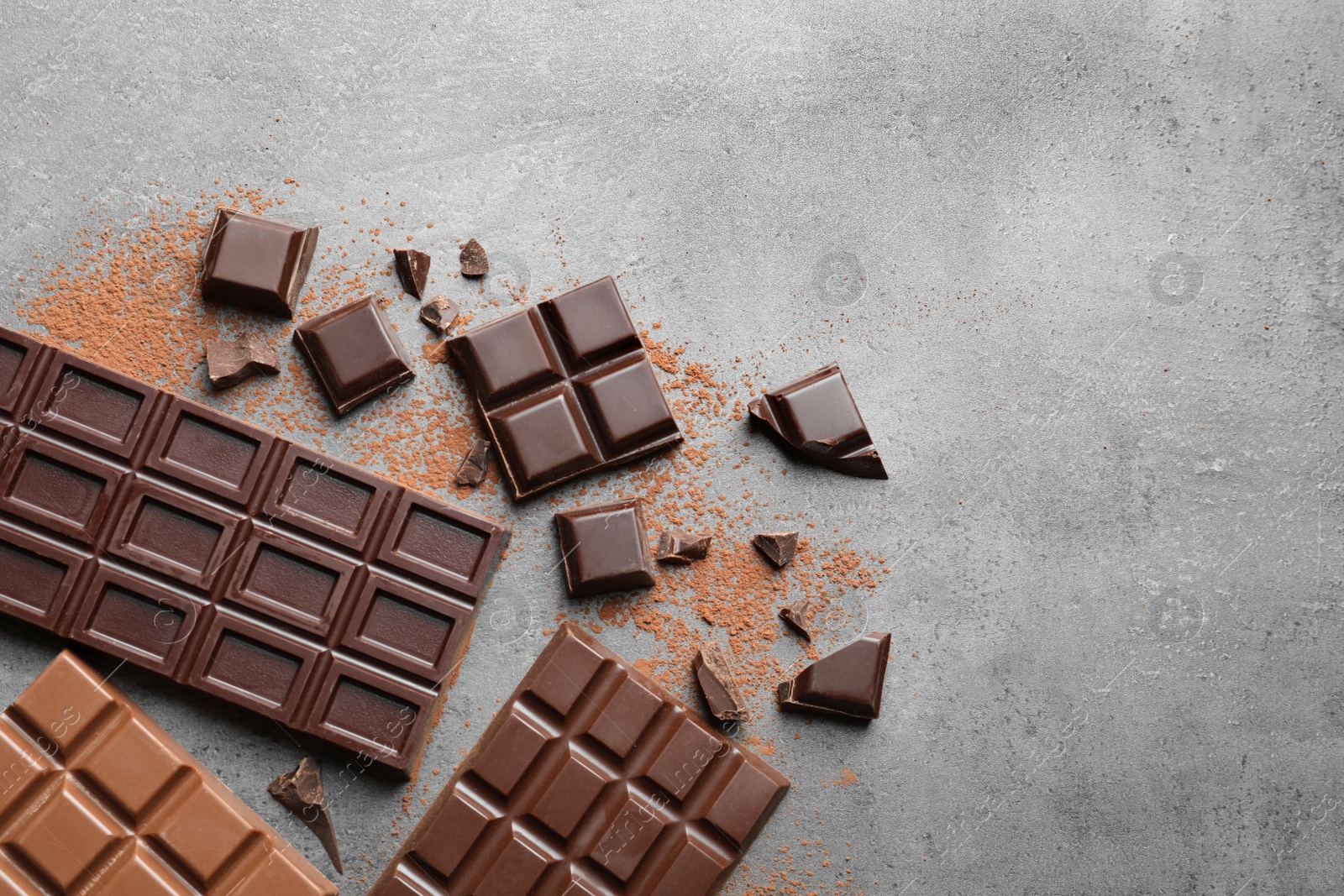 Photo of Different kinds of chocolate on grey background, flat lay. Space for text