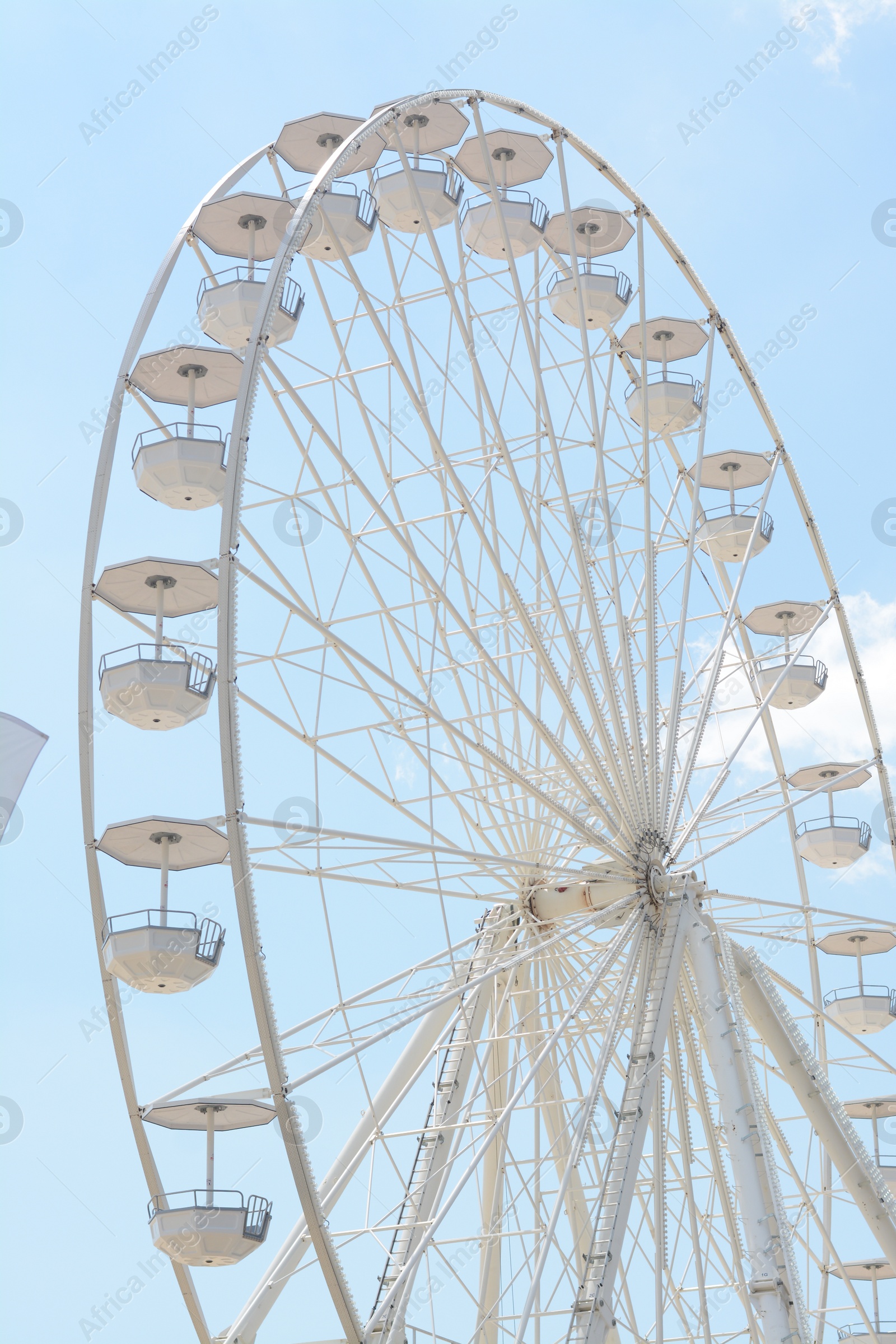 Photo of Large white observation wheel against blue cloudy sky, low angle view