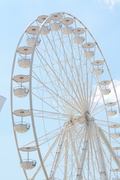 Large white observation wheel against blue cloudy sky, low angle view