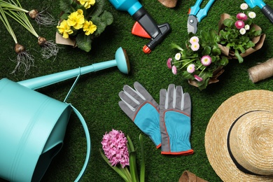 Photo of Flat lay composition with gardening equipment and flowers on green grass