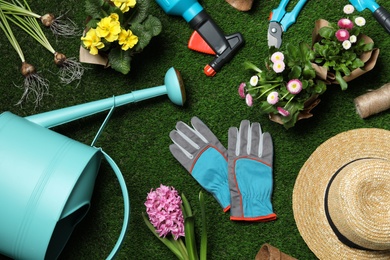 Flat lay composition with gardening equipment and flowers on green grass