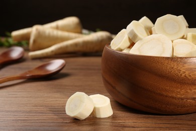 Photo of Fresh ripe parsnip in bowl on wooden table. Space for text