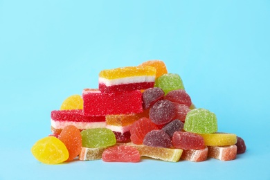 Photo of Pile of delicious bright jelly candies on light blue background