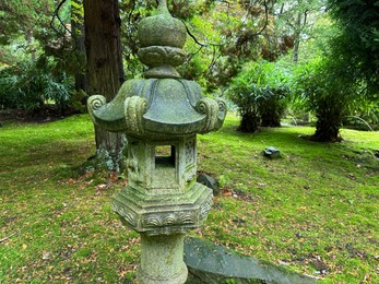 Photo of Stone lantern, bright moss and fallen leaves in Japanese garden