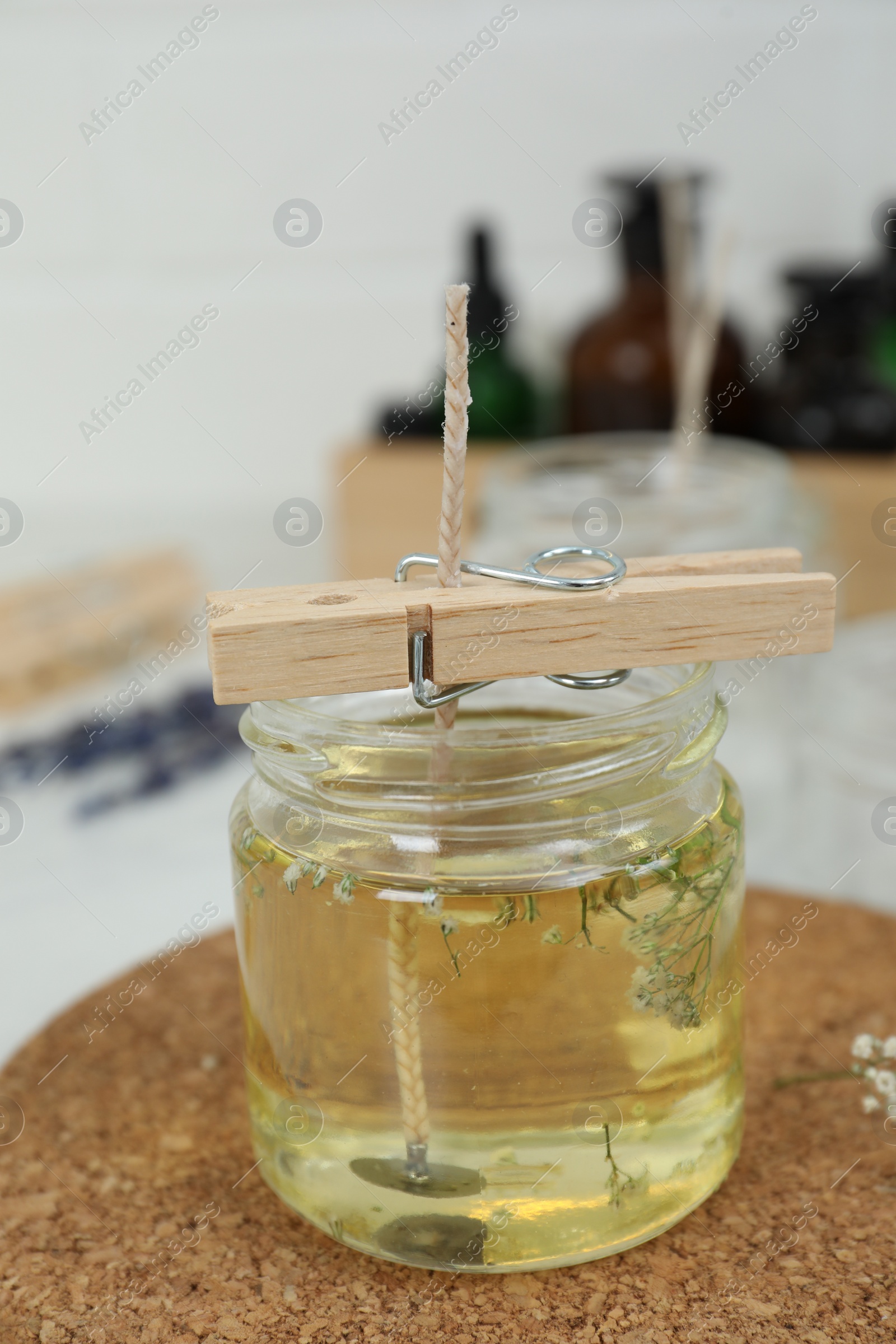 Photo of Glass jar with melted wax on white table. Handmade candle