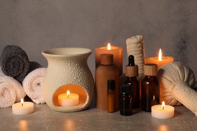 Photo of Aromatherapy. Scented candles and spa products on gray textured table