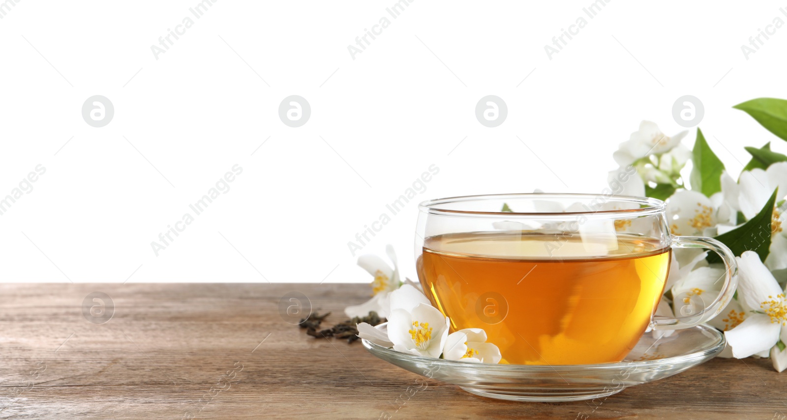 Photo of Glass cup of aromatic jasmine tea and fresh flowers on wooden table against white background. Space for text