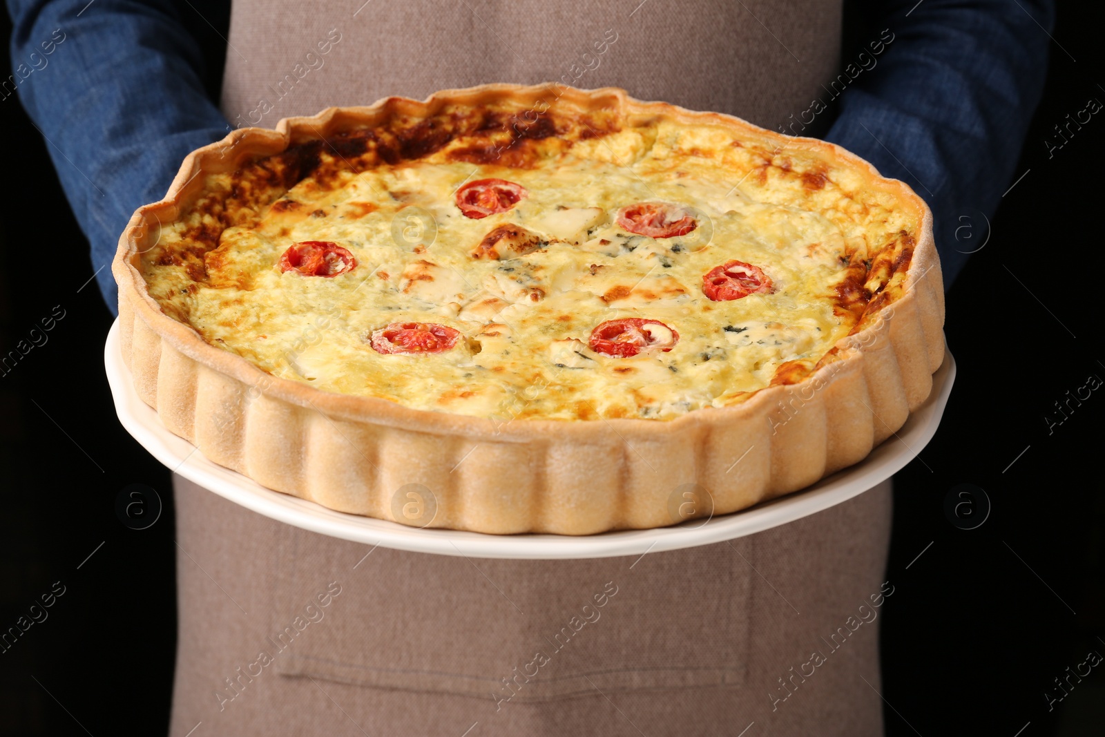 Photo of Woman with delicious homemade cheese quiche on black background, closeup