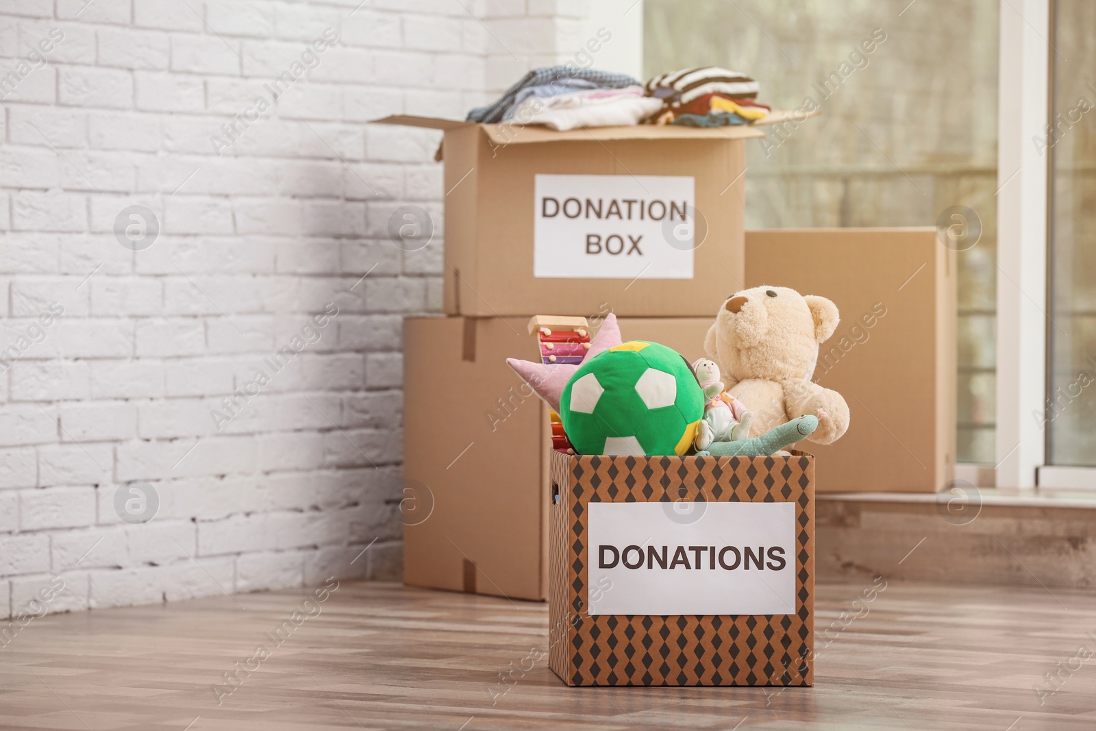 Photo of Donation boxes with toys and clothes on floor indoors