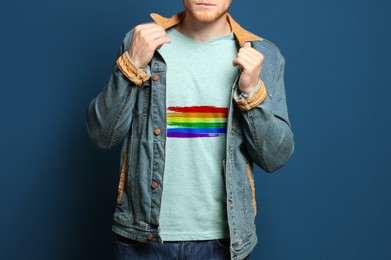 Image of Young man wearing t-shirt with image of LGBT pride flag on blue background