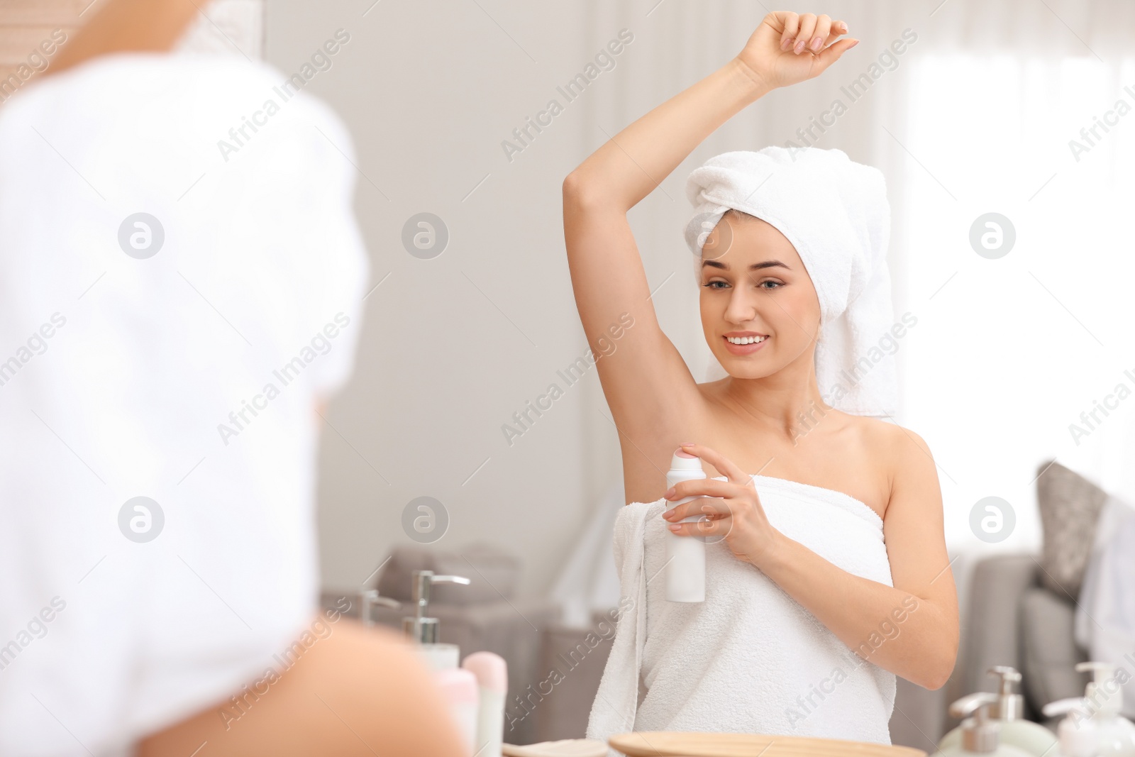 Photo of Beautiful young woman applying deodorant after shower in bathroom