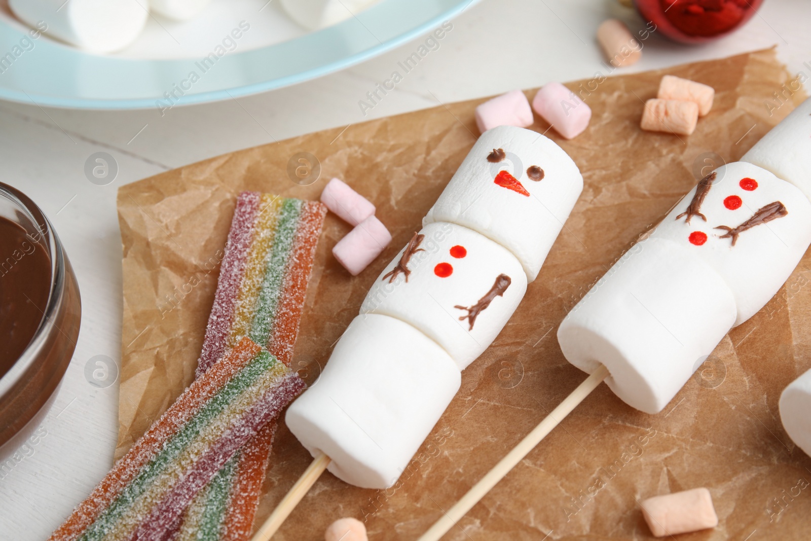 Photo of Funny snowman made of marshmallows on white table, closeup