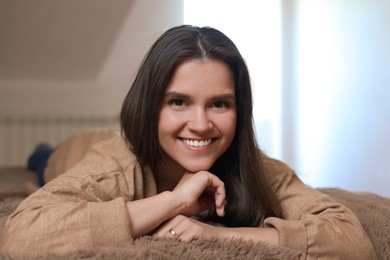 Portrait of beautiful young woman lying on bed at home