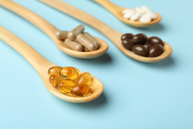 Photo of Wooden spoons with different dietary supplements on light blue background