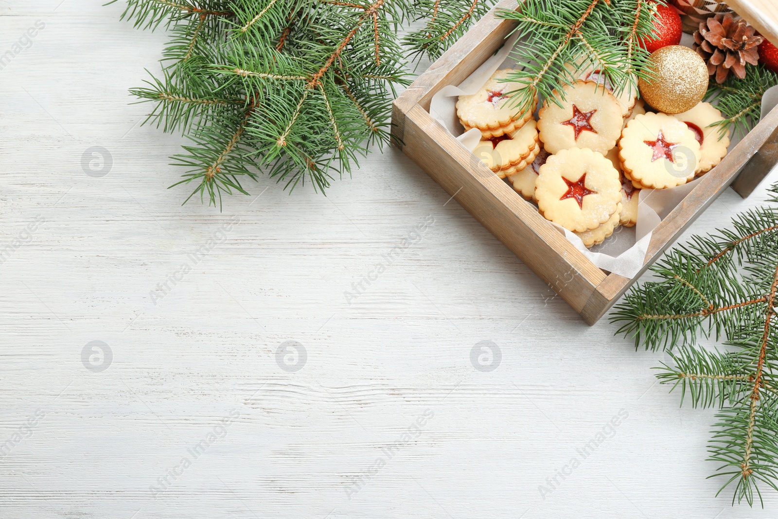 Photo of Traditional Christmas Linzer cookies with sweet jam and fir branches on wooden background, top view