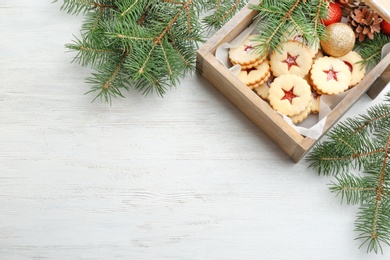 Traditional Christmas Linzer cookies with sweet jam and fir branches on wooden background, top view