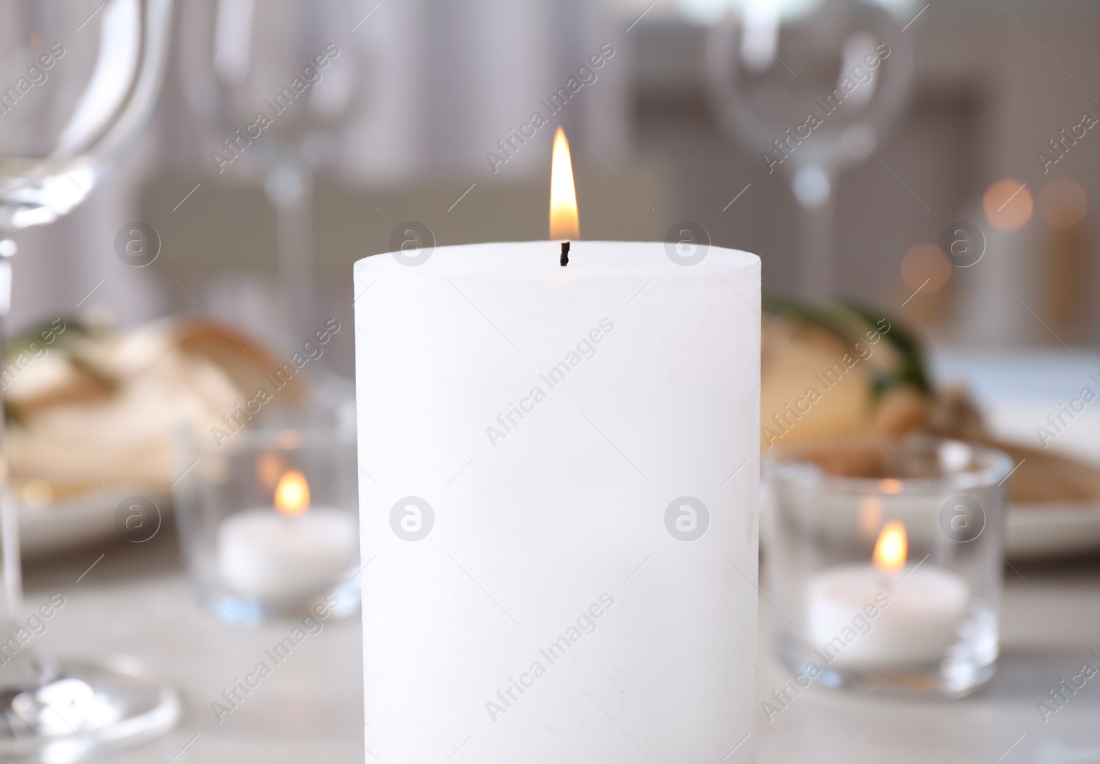 Photo of White burning wax candle on table, closeup