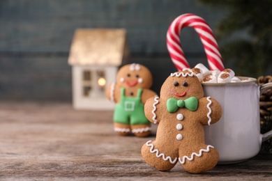 Photo of Gingerbread man and hot drink on wooden table, space for text