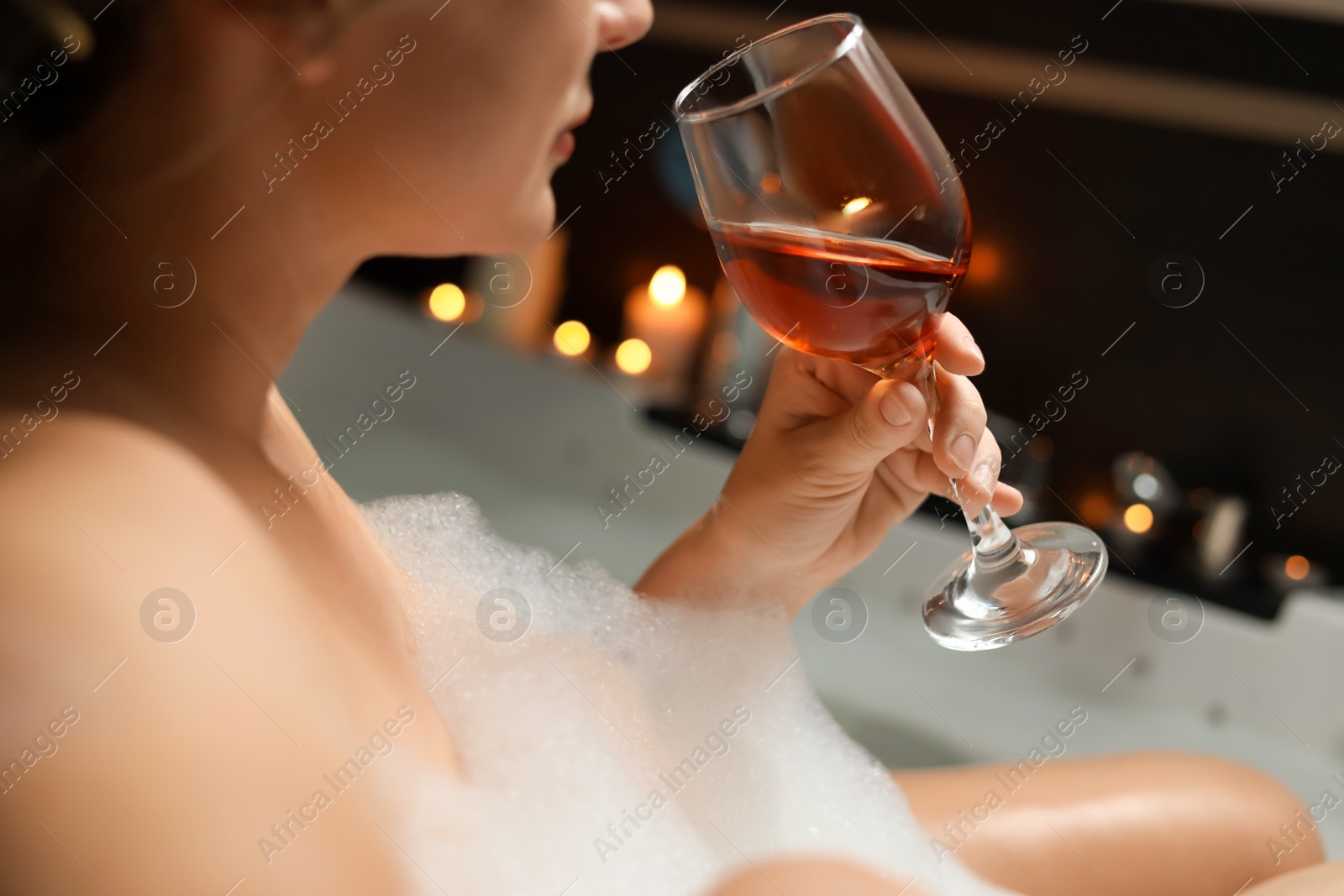 Photo of Woman drinking wine while taking bubble bath, closeup. Romantic atmosphere