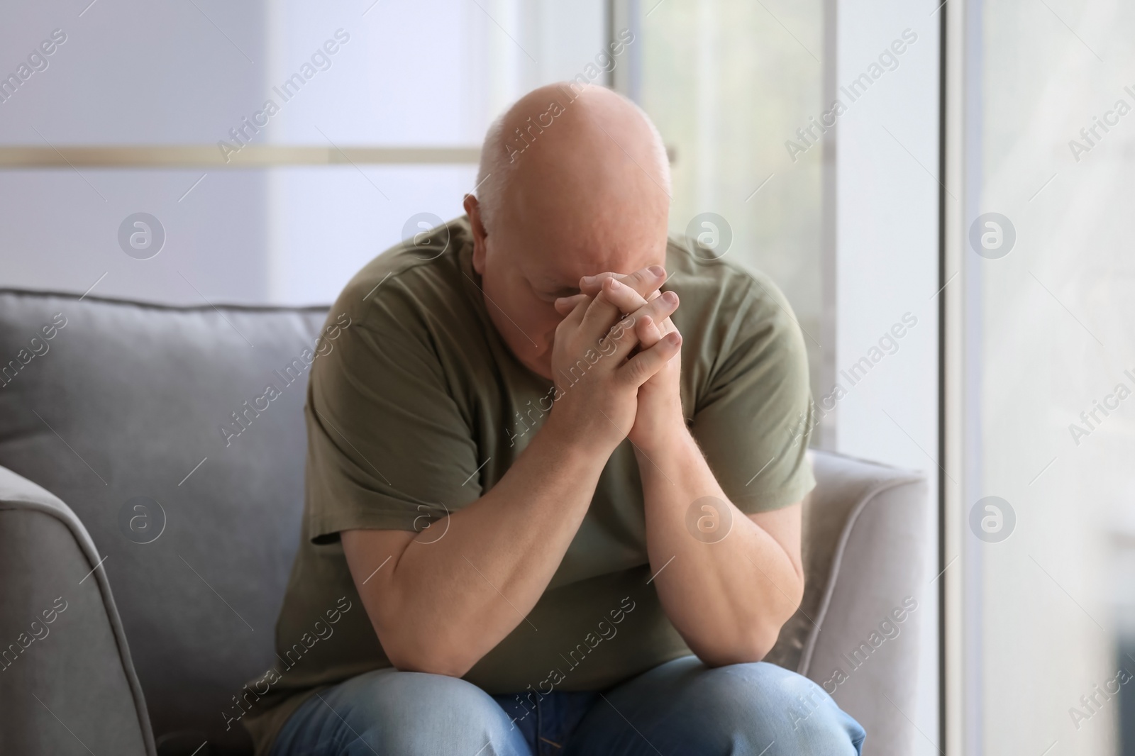 Photo of Depressed senior man sitting in armchair indoors