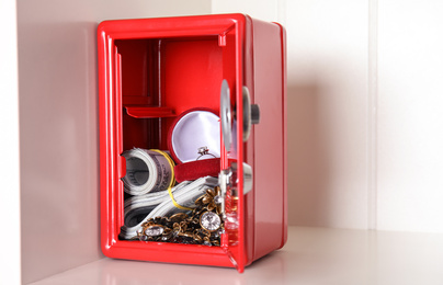 Photo of Open red steel safe with money and jewelry on shelf. Space for text
