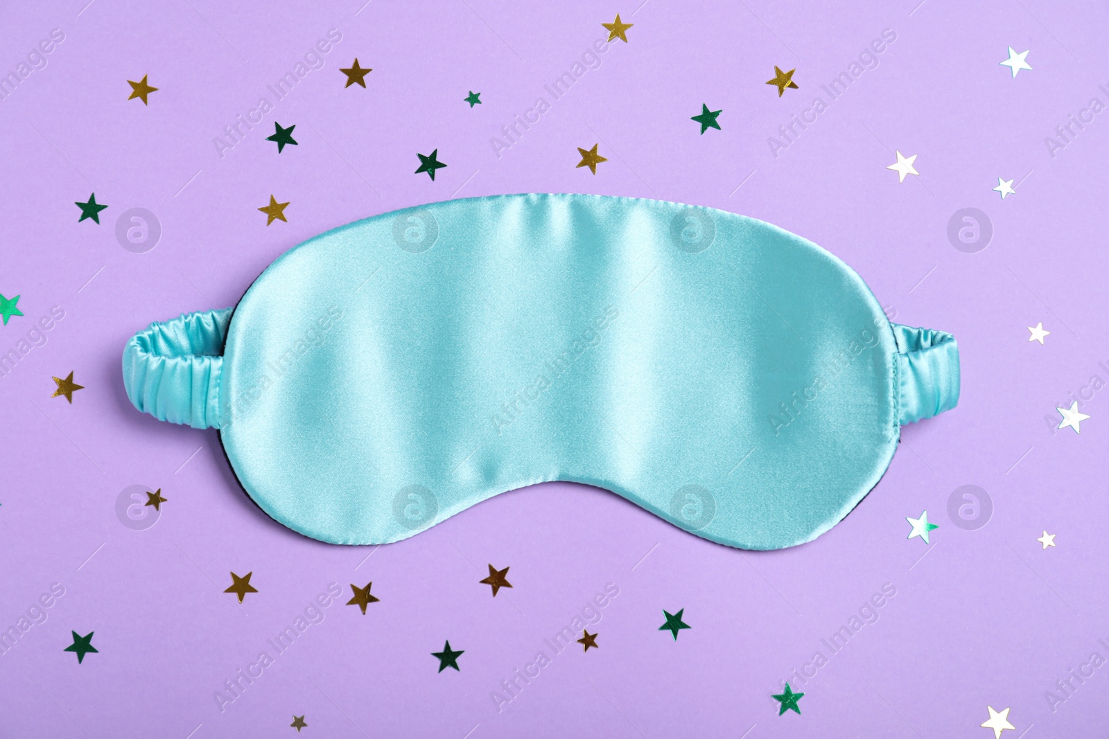Photo of Sleeping mask and glitter on violet background, flat lay. Bedtime accessory