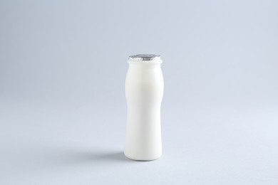 Photo of Tasty yogurt in bottle on light grey background